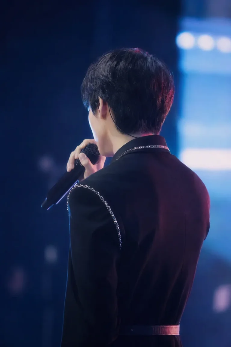 A faceless Korean idol-actor stands near a glowing Seoul stage, suggesting a debut drama about fandom and music.