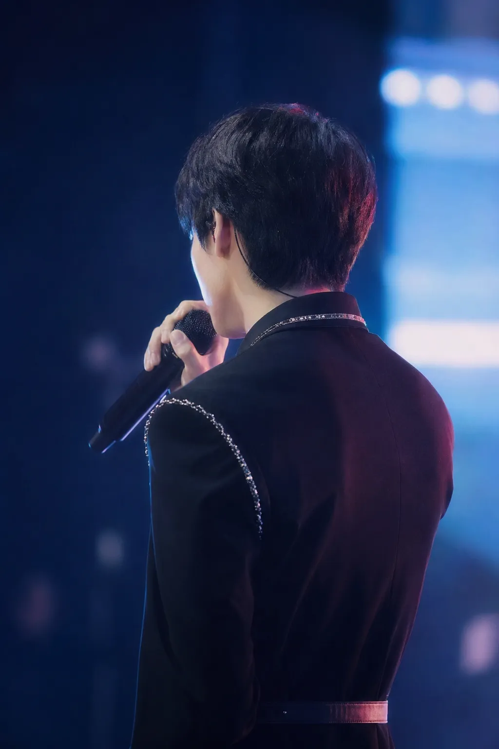 A faceless Korean idol-actor stands near a glowing Seoul stage, suggesting a debut drama about fandom and music.