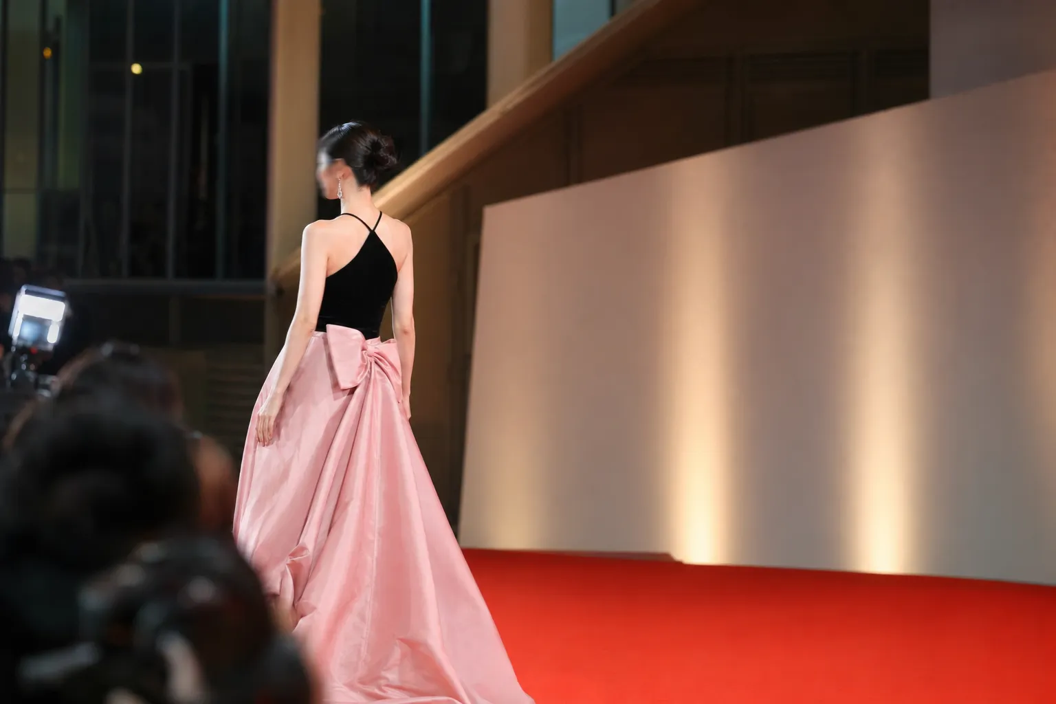 A Korean artist in black-and-pink evening wear walks a minimalist red carpet.