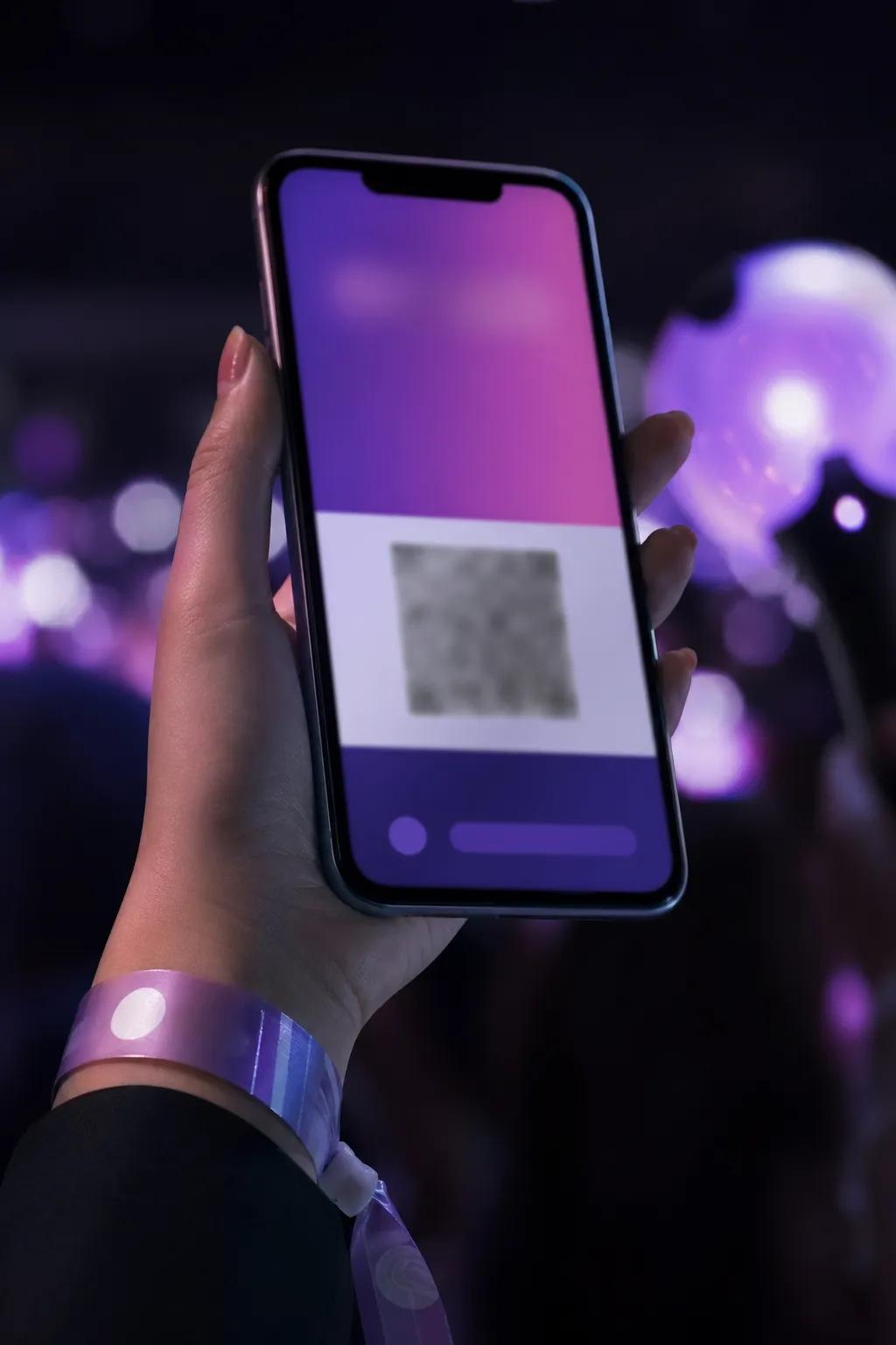 Close-up of a smartphone used for mobile concert entry with purple concert lights blurred behind it.