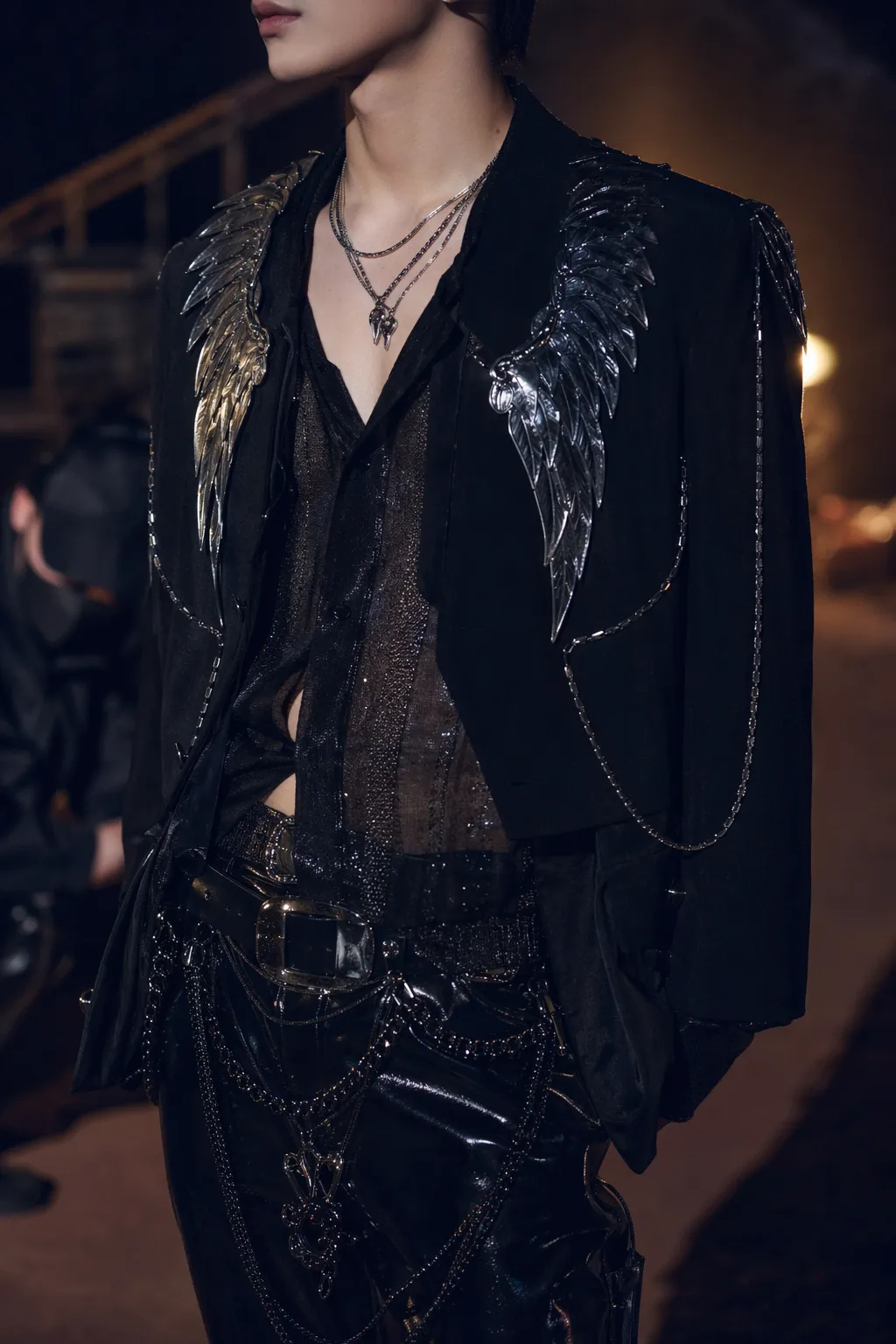 Futuristic K-pop stage styling with black chrome angelic details in a cinematic backstage setting.